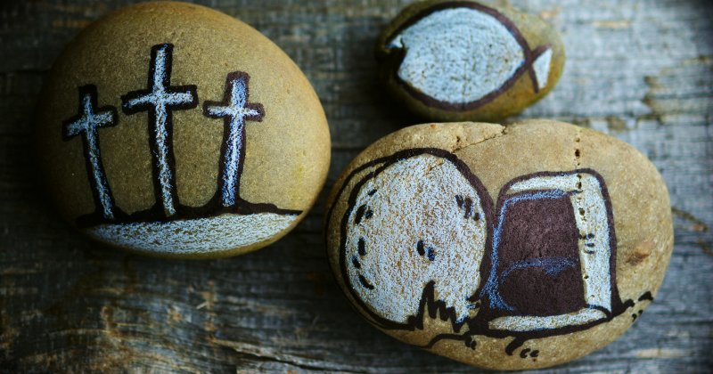 Bemalte Steine mit christlichen Symbolen: Kreuz, Fisch, geöffnetes Grab
